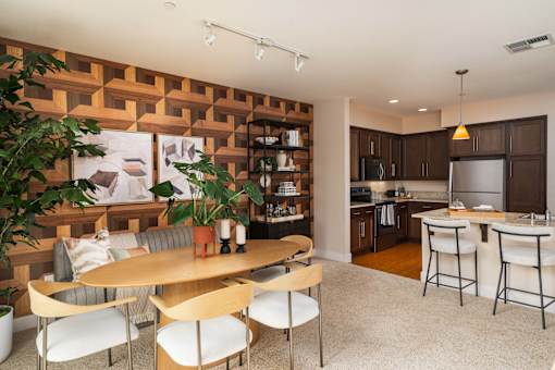 A modern kitchen with a wooden wall panel and a dining table with chairs.
