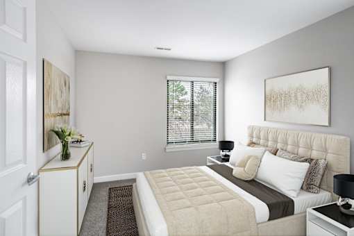 A bedroom with a large bed and a window with blinds.