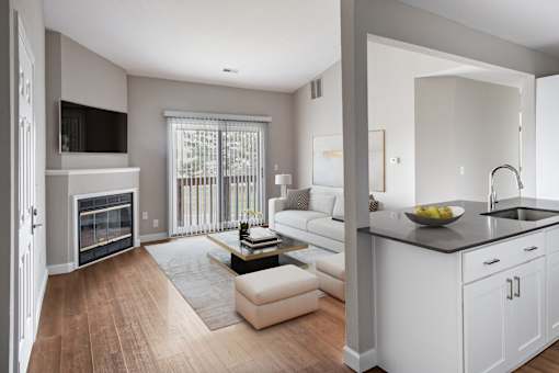 A modern living room with a fireplace and a kitchen area.