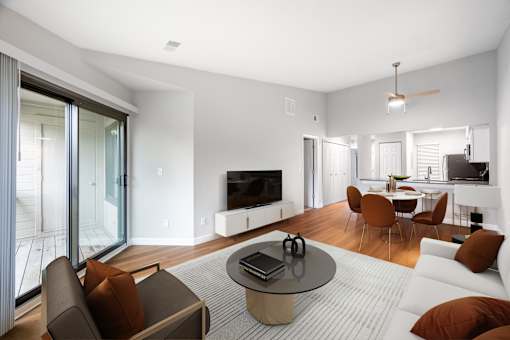 A modern living room with a flat screen TV, a glass table, and a white couch.