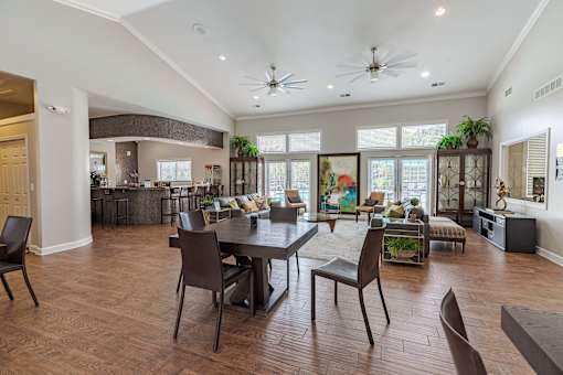 A modern dining room with a dark wood floor and a large table surrounded by chairs.
