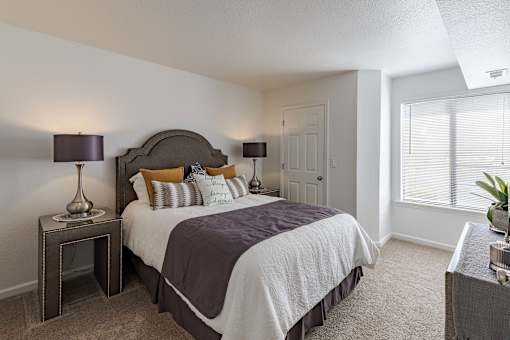 A bedroom with a large bed and a nightstand with a lamp.