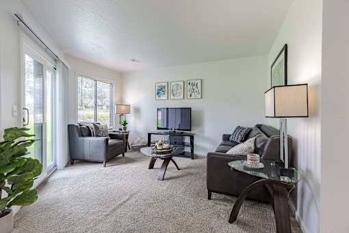 A living room with a grey couch, a black coffee table, and a flat screen TV.