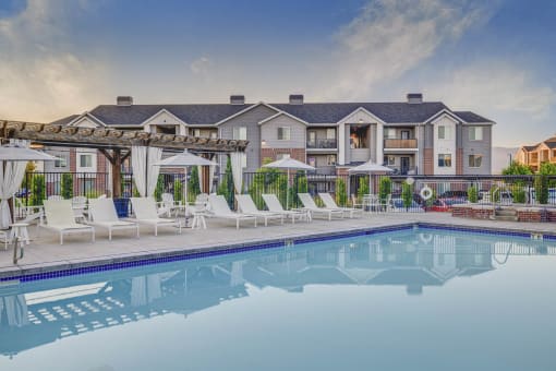 a swimming pool with chairs and umbrellas and a building in the background