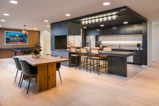 the kitchen and dining area of a modern home with a wood floor and black cabinets
