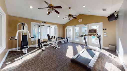 A home gym with a treadmill, weights, and exercise equipment.