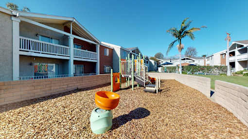 A playground with a slide and a green toy in the foreground.