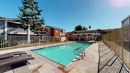 A swimming pool surrounded by a fence and benches.