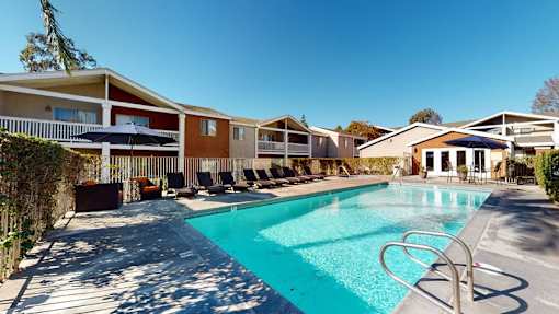 A swimming pool surrounded by lounge chairs and buildings.