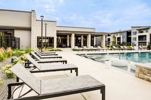A poolside area with sun loungers and a building in the background.
