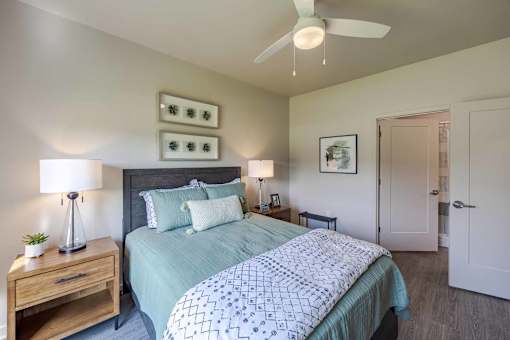 A bedroom with a bed, nightstand, and a ceiling fan.