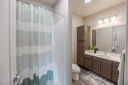 A bathroom with a white toilet, a sink, a mirror, and a shower with a glass door.
