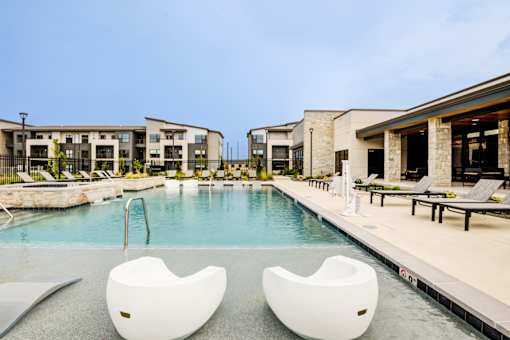 Two white chairs are placed in the middle of a pool.