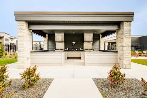A modern house entrance with a stone pillar and a concrete walkway.