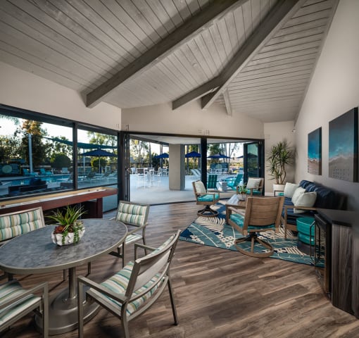 a room with a table and chairs and large open windows