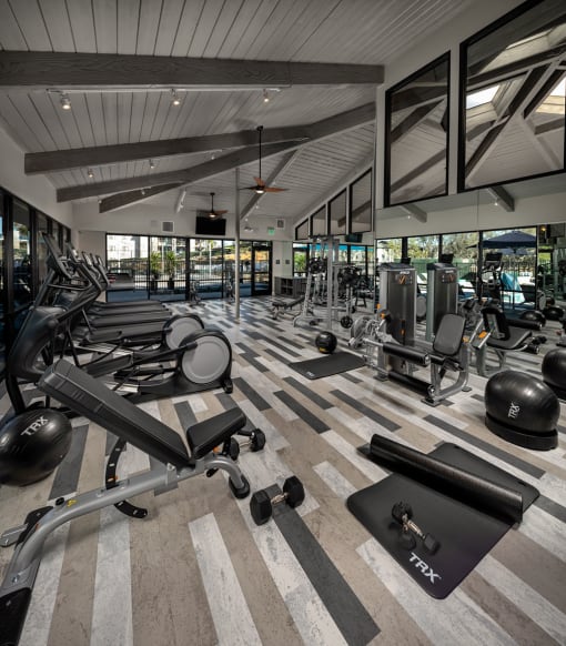a gym with work out machines and windows