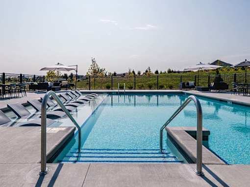 Pool with lounge chairs at Velo Village Apartments near Whitnall Park.