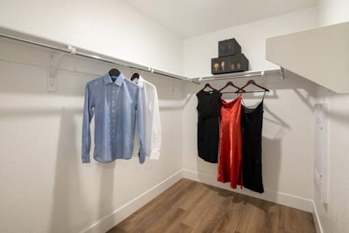 A row of clothes are hung on a rail in a room.