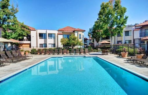 A swimming pool in front of apartment buildings. at The Casas Apartments, San Diego