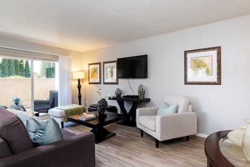 A living room with a purple couch, a white chair, and a black coffee table at The Casas Apartments, California