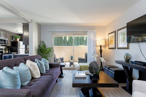 A modern living room with a grey couch and a coffee table at The Casas Apartments, San Diego, California