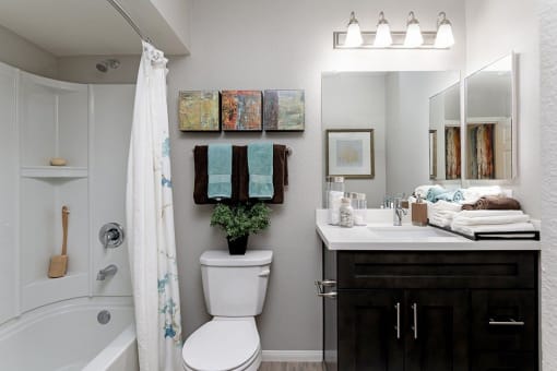A bathroom with a white toilet, a white sink, and a white bathtub at The Casas Apartments, San Diego, CA, 92126