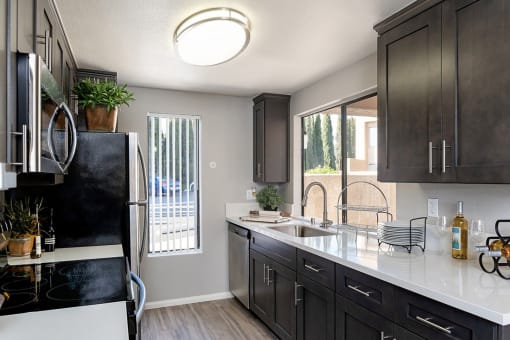 A kitchen with black cabinets and a black fridge at The Casas Apartments, San Diego, CA, 92126