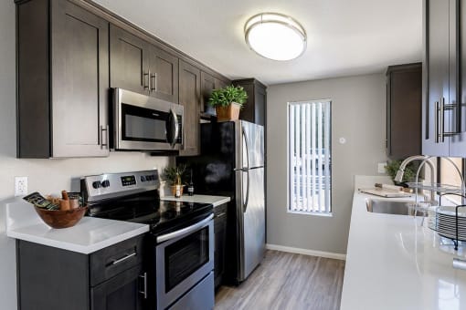 A modern kitchen with dark wood cabinets and stainless steel appliances at The Casas Apartments, California, 92126