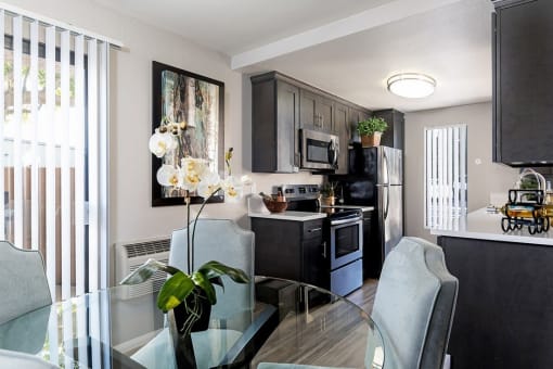 A modern kitchen with a glass table and chairs at The Casas Apartments, California