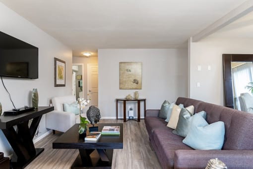 A living room with a couch, a coffee table, and a television at The Casas Apartments, San Diego, 92126