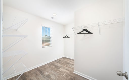 a walk in closet with white walls and a window