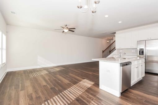 a kitchen and living room with a staircase in the background