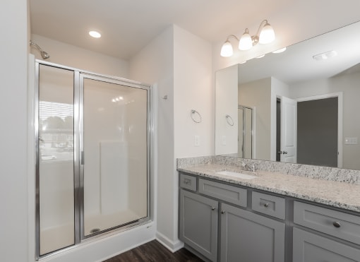 a bathroom with gray cabinets and granite countertops