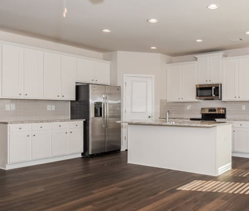 a kitchen with white cabinets and a stainless steel refrigerator