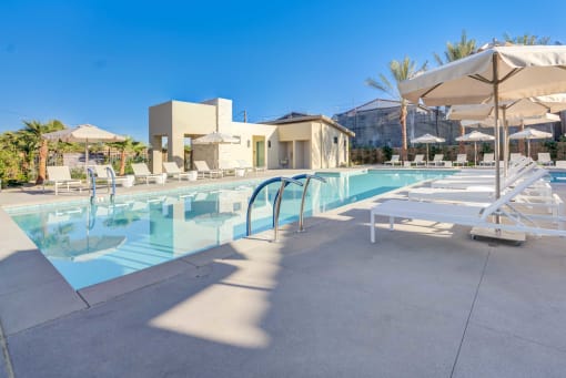 a swimming pool at a resort with chairs and umbrellas