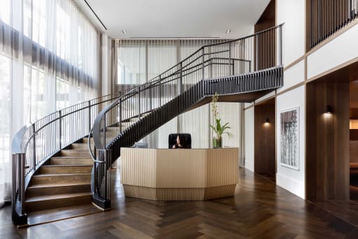 the lobby of a hotel with a staircase and a reception desk