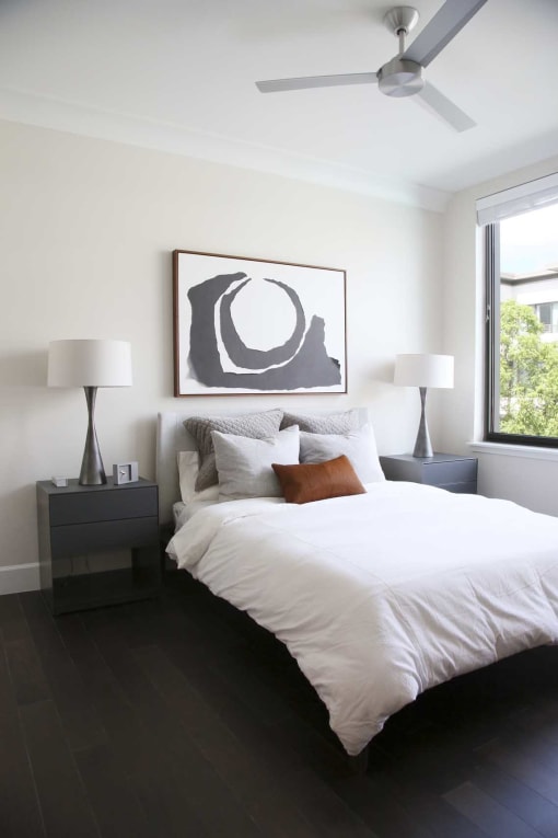 a bedroom with a white bed and a painting on the wall