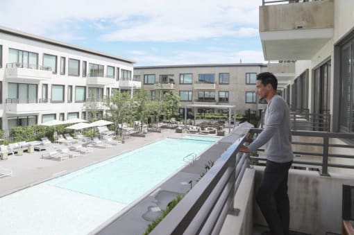 a man standing on a balcony overlooking a swimming pool