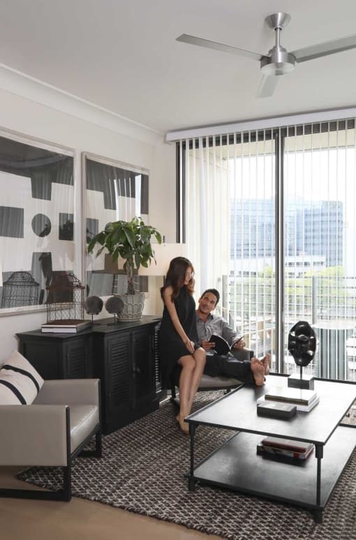 two people sitting in a living room looking at a laptop