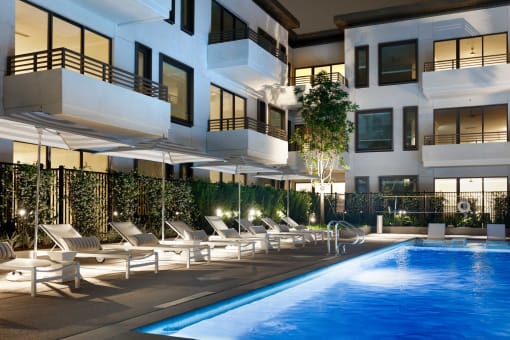 a swimming pool in front of an apartment building at night