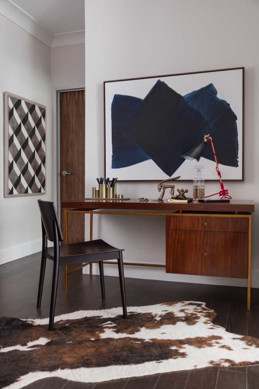 a desk with a chair and a painting on the wall