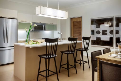 a kitchen with a bar with three black stools