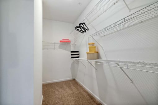 a walk in closet with white walls and carpet