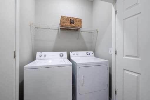 a white laundry room with two washes and a dryer