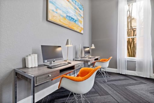 a room with a desk with a computer and chairs