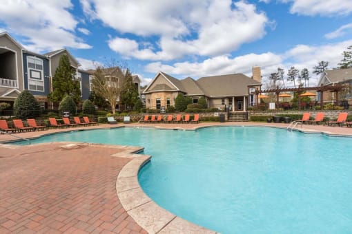 a large swimming pool with chairs in front of a house