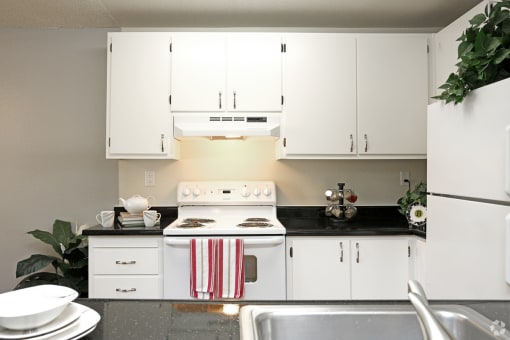 a kitchen with white appliances and white cabinets and black counter tops