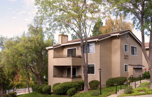 the exterior of a house with trees and a sidewalk