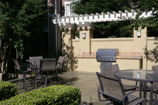 a patio with a grill and a table and chairs
