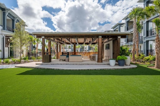a covered patio with a lawn in front of some apartments